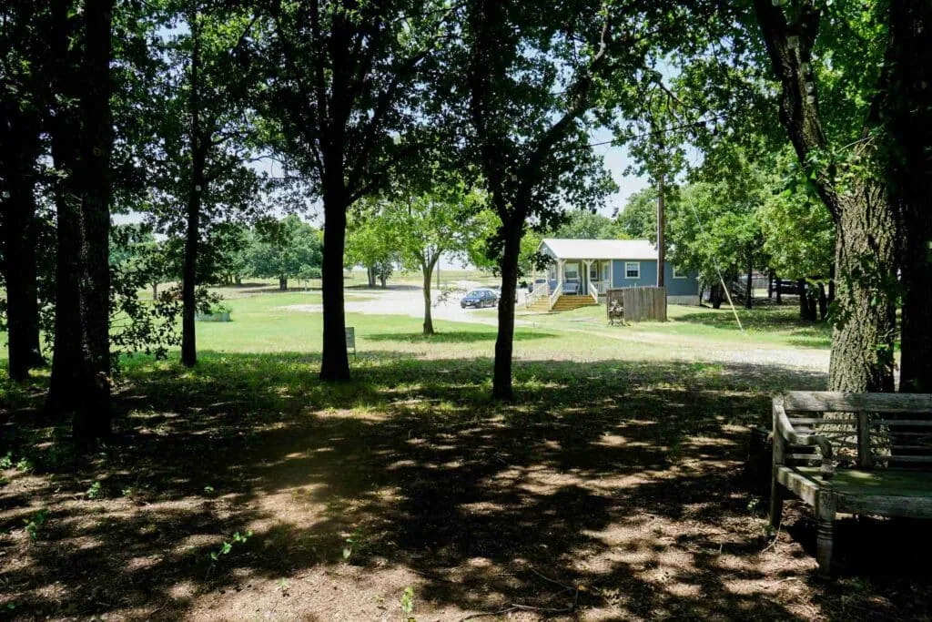 Oak shade over the grounds at Waterfront Hideaway Ranch, with a cabin beyond
