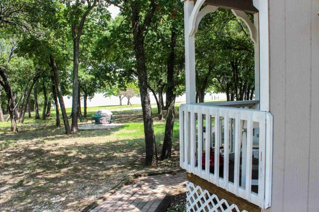 A cabin porch looking out over the oaks and the shared grounds